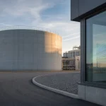 Exterior view of a large chilled-water thermal energy storage tank at a district cooling plant in soft morning light.