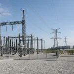 High-voltage substation and transmission lines near an industrial campus, illustrating site-specific data center power grid constraints.